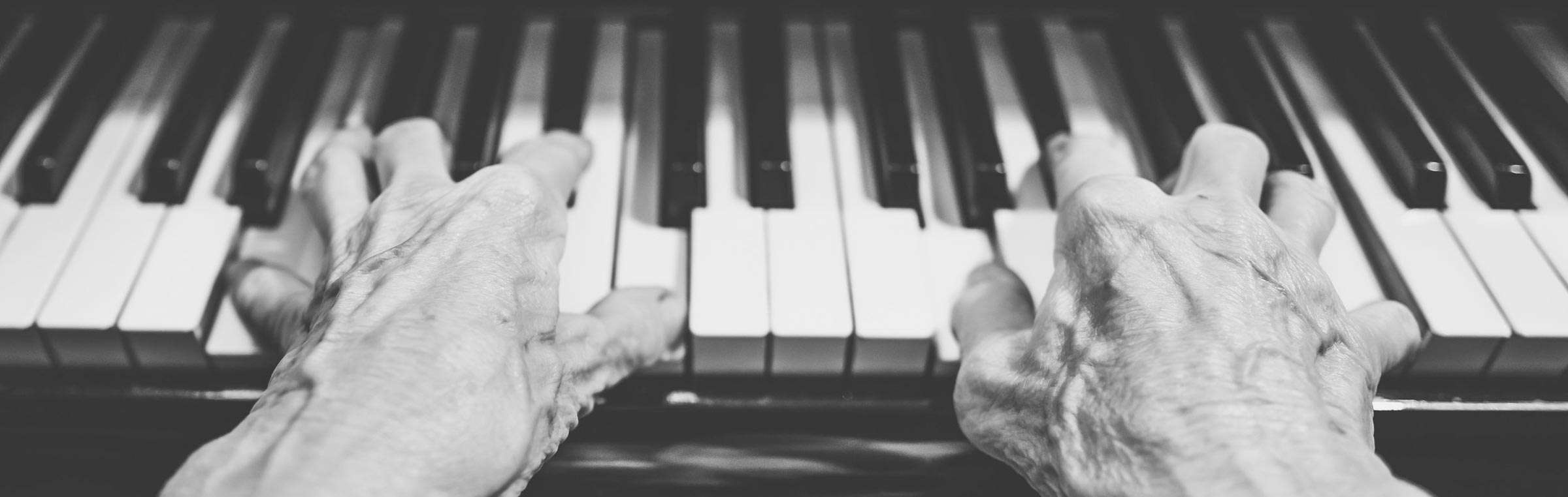 Hands on a piano in black and white.